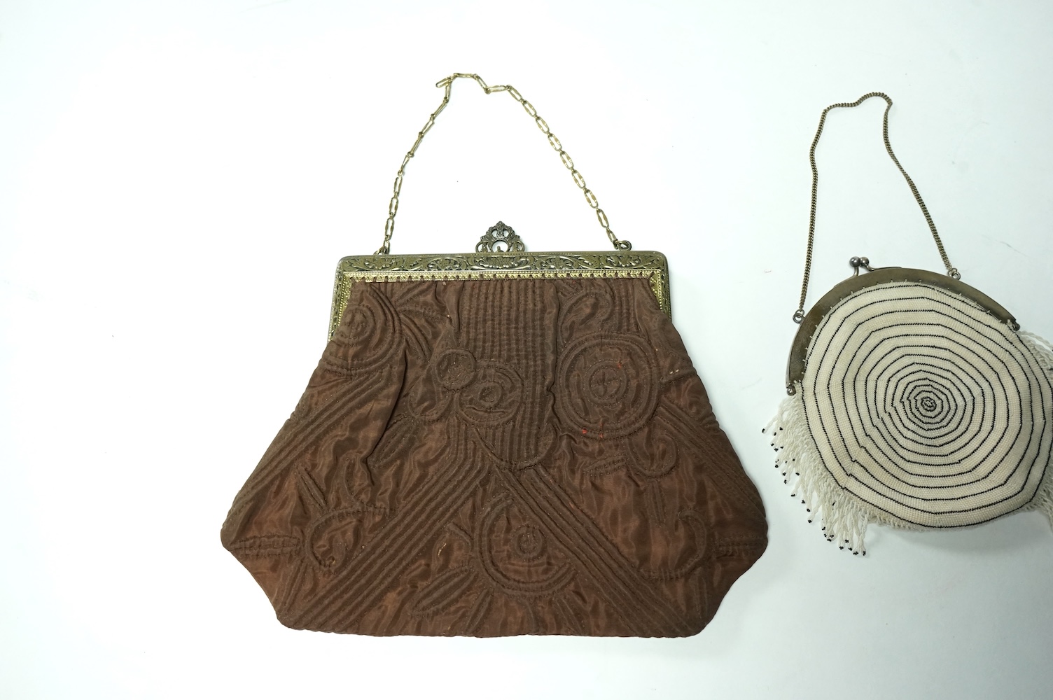 A 1930’s black and white finely beaded evening bag with a German 830 standard stamped metal frame together with a marcasite framed black satin bag and a brown quilted bag with an ornate paste set gilt frame. Largest 21.5